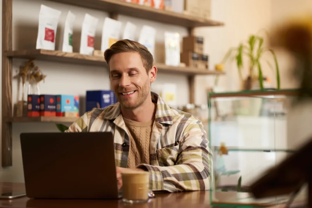 Small business owner working on a laptop in his café, planning a new website