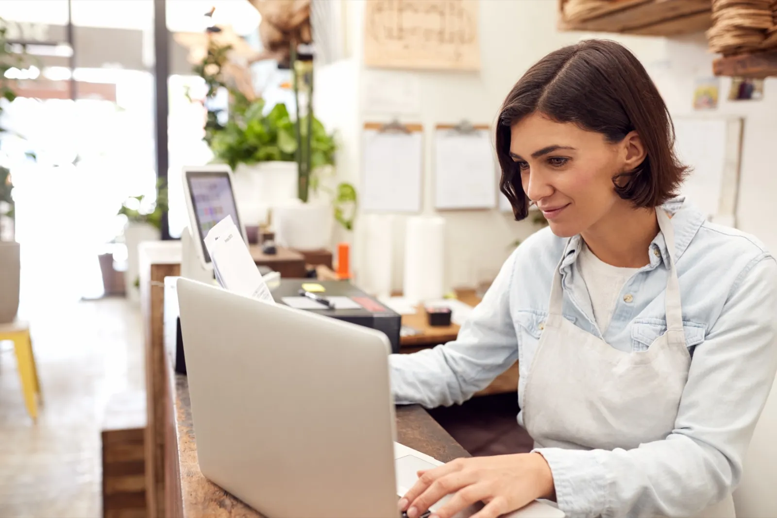 Shop owner sending an email newsletter from her laptop in her store